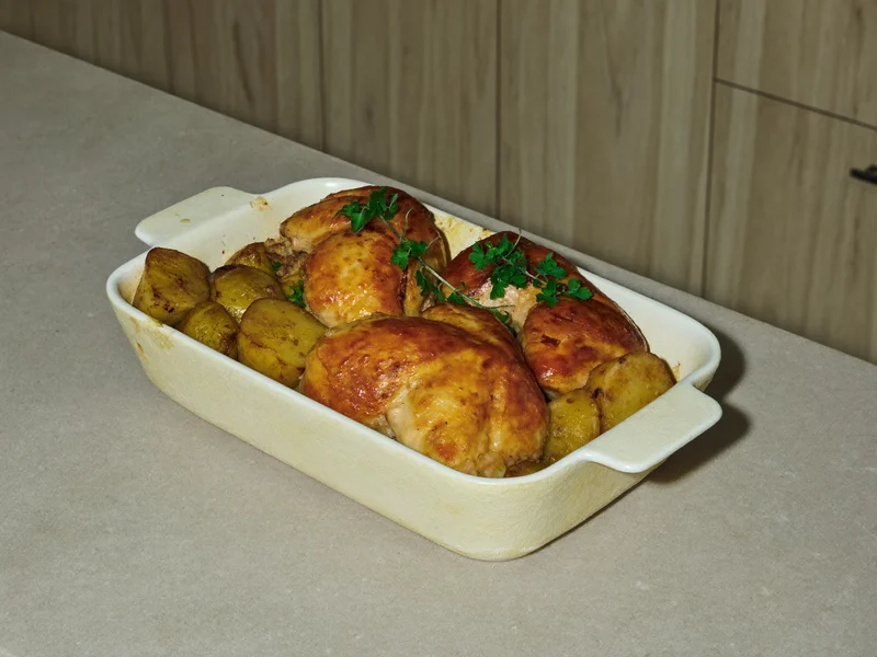 Casseruola di pollo e patate con erbe aromatiche, vista dall'alto sul piano della cucina.